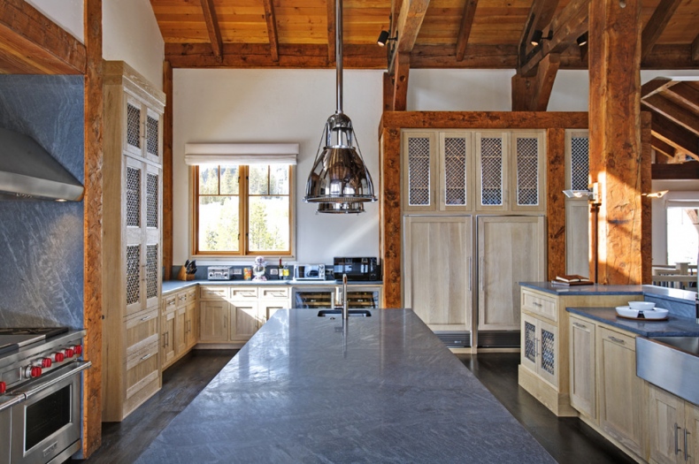 Suspended lights match the rustic kitchen’s stainless steel counter top